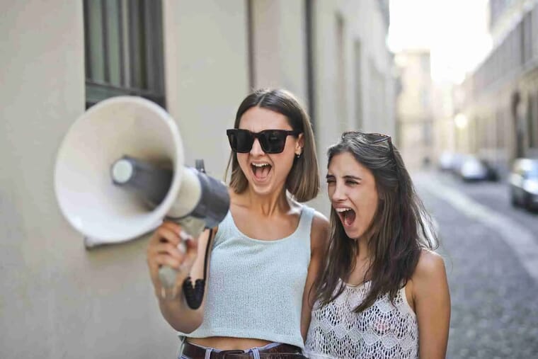 cheerful young women screaming into loudspeaker