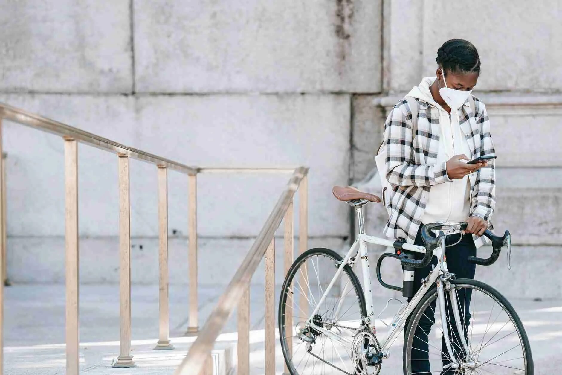african american woman with smartphone and bicycle